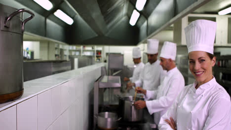 cocineros trabajando en la estufa con uno sonriendo a la cámara