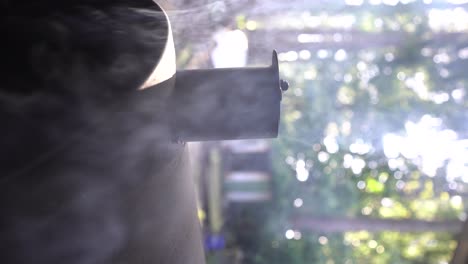 close up of a partially closed barbeque grill chimney, charcoal and wood burning, smoke, vertical orientation