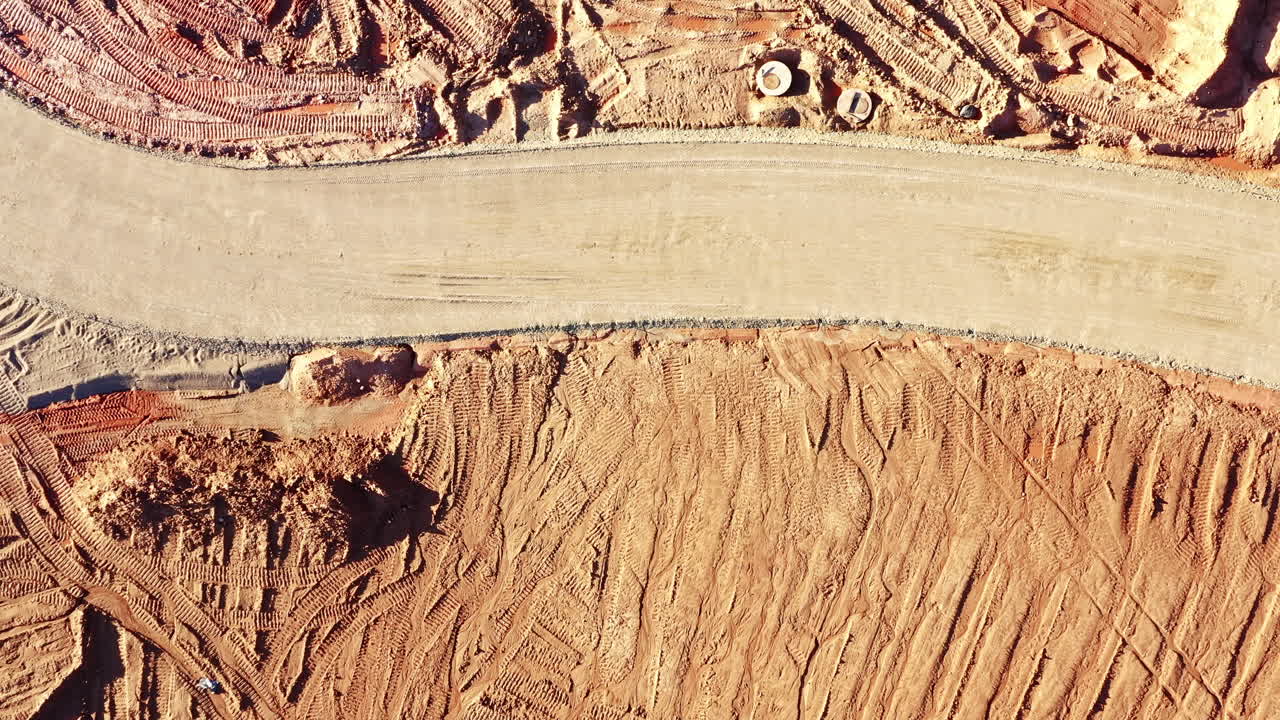 Aerial View of Winding Construction Site Road With Sandy Terrain in top down view