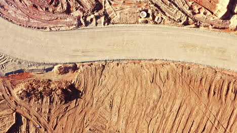aerial view of winding construction site road with sandy terrain in top down view