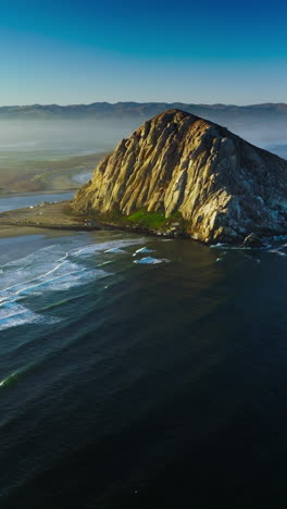 Amazing sunny morning at Morro Bay, California, USA. Lovely white waves arriving to the shore calmly. Hazy horizon at backdrop. Vertical video