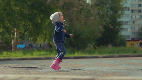 little child happily jumps in deep puddle