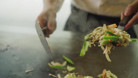 chef cooking vegetable teppanyaki on iron griddle