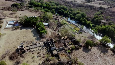 panoramic aerial view of ex hacienda san jacinto ixtoluca ruins beside river, la mezquitera, morelos. estate ruins bordered by river and surrounded by dry terrain and greenery