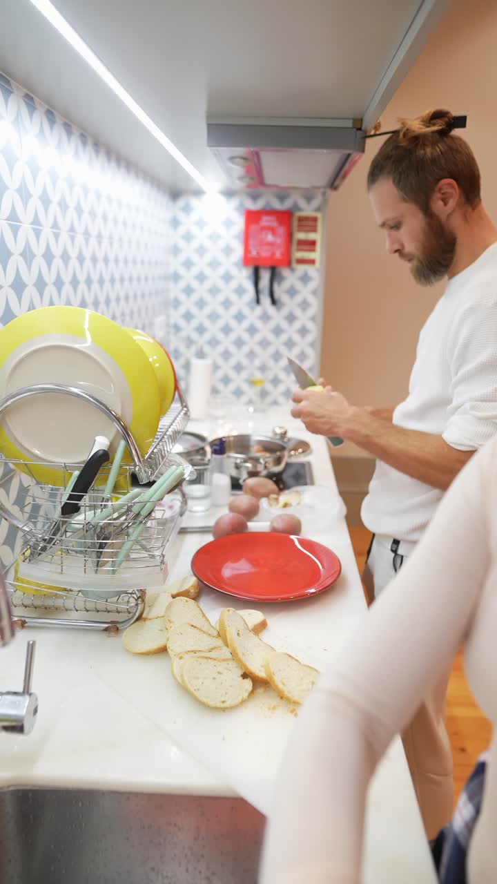 una pareja preparando la cena en una cocina desordenada