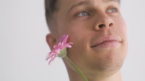 close up of young man smiling and holding a flower