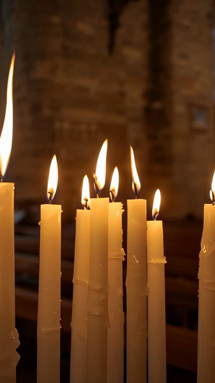 Video verticale: macchina da presa che si allontana, candele bianche accese che tremolano e cera che gocciola in chiesa per la preghiera