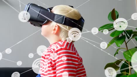 network of digital icons against caucasian boy wearing vr headset at home