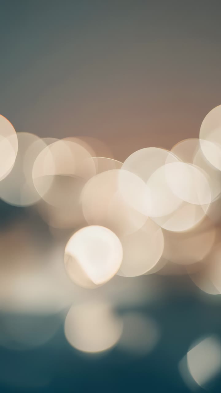 Vertical video: Shifting focus, bokeh cluster emerging in dim interior, bright circle moving left