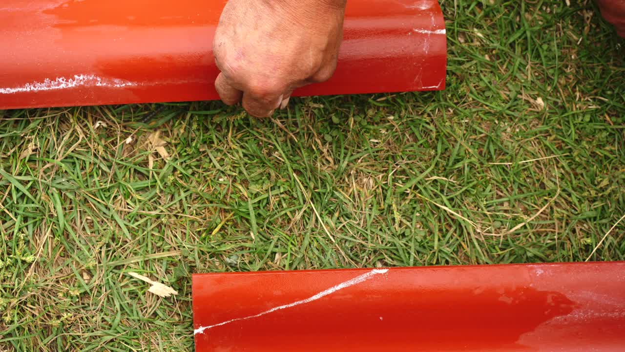 primer plano de la mano del trabajador masculino haciendo mediciones en el techo de acero rojo al aire libre. clip. materiales y equipos para el hogar