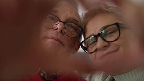 portrait of older retired couple making heart with their hands