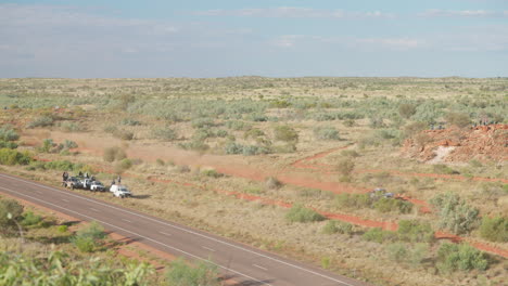 4K-Slow-Motion-Drone-Of-Finke-Desert-Race-Trophy-Truck-Racing-Alongside-Highway,-Australia