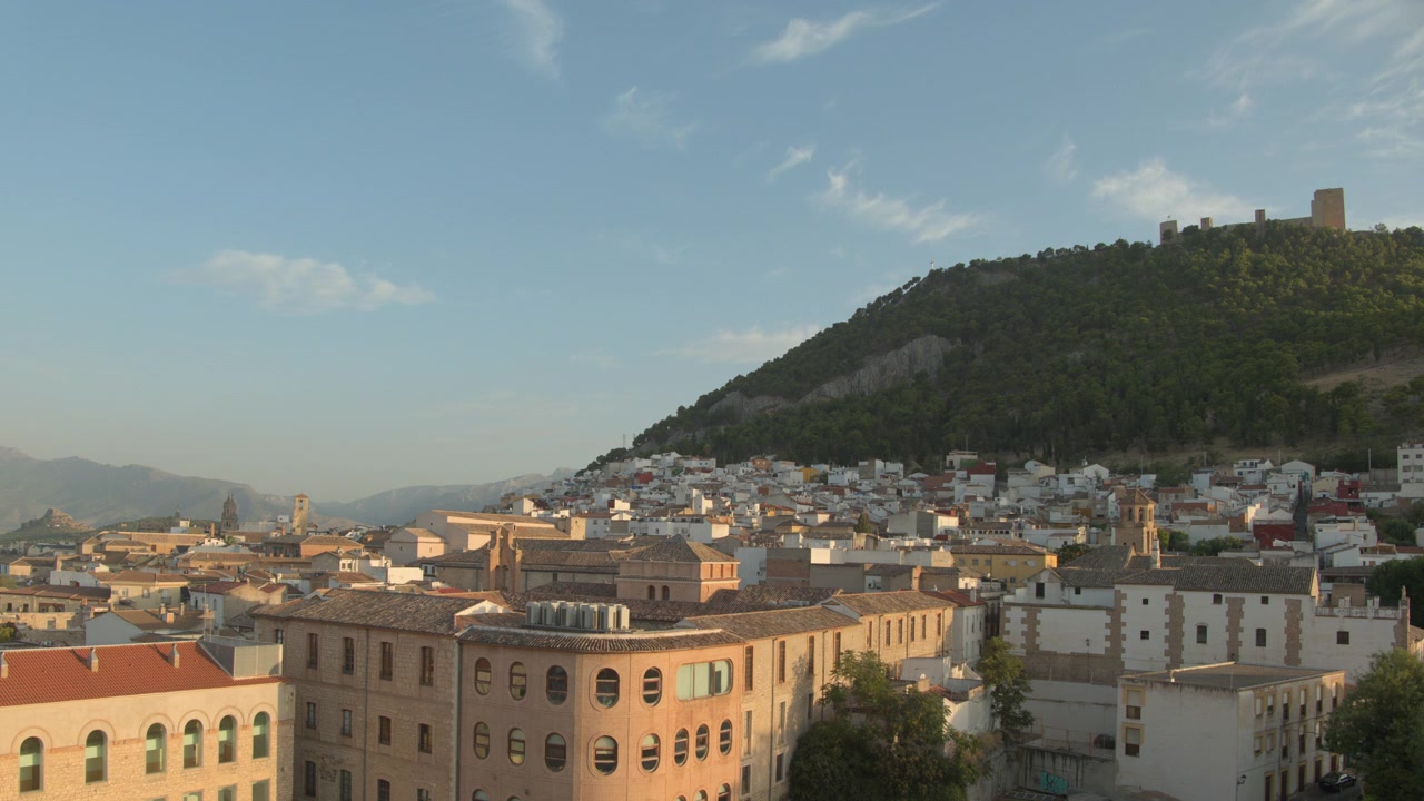 Un time-lapse grandangolare che cattura il drastico calo della luce diurna ambientale durante l'eclissi solare totale del 12 agosto 2026, sulla città di Jaén, Spagna. L'inquadratura statica dall'alto mostra i tetti della città.