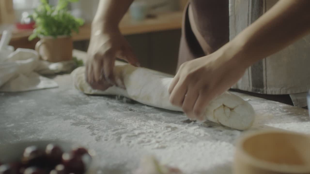 Hands Rolling Dough on a Floured Kitchen Countertop