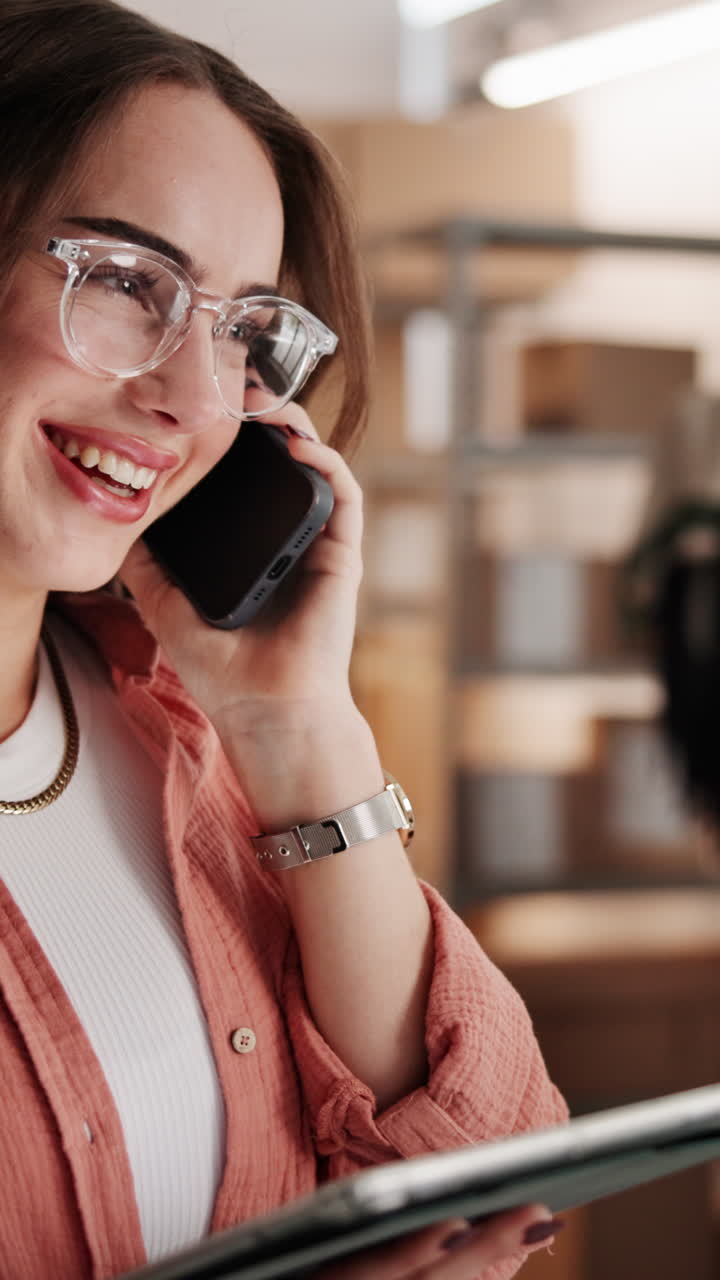 Giovane donna sorridente che parla al telefono mentre tiene un tablet