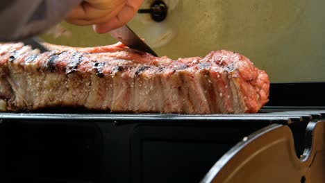 cutting-a-slice-of-delicious-smoked-grilled-pork-belly-meat-on-grill-barbecue