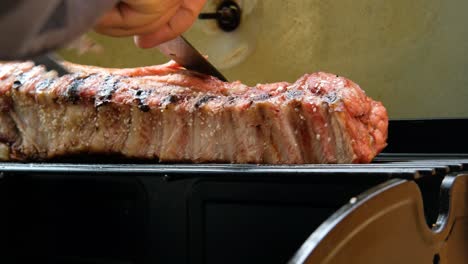 cortar una rebanada de deliciosa carne de panceta de cerdo ahumada a la parrilla en la parrilla