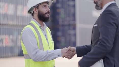 inversor de mediana edad o ejecutivo, gerente apretón de mano con ingeniero masculino profesional, trato de trabajar es exitoso o acordar la inversión juntos en el patio de carga de contenedores. apretando la mano felicitar cuando el trabajo hecho.