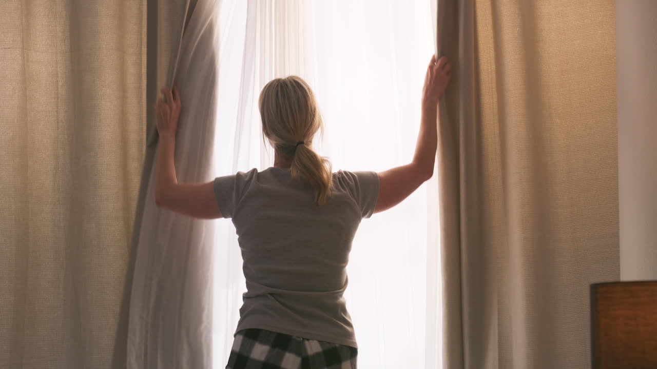 Woman Opening Curtains in Bedroom