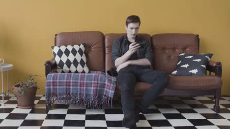 young man using smartphone on a couch