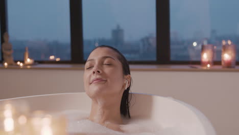 mujer escuchando música con auriculares mientras se baña en la bañera 1