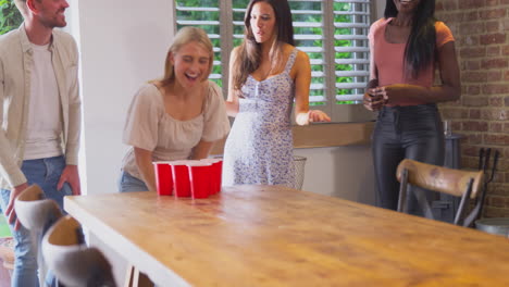 Grupo-Multicultural-De-Amigos-Jugando-Juntos-En-Casa-Lanzando-Una-Pelota-En-Un-Vaso-De-Papel