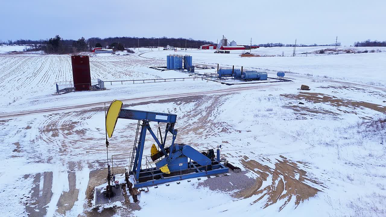 Pompa di estrazione petrolifera in funzione in un campo invernale, che estrae combustibili fossili per energia, Michigan, USA.