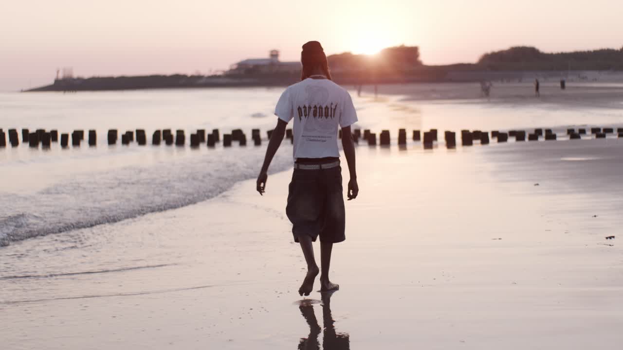 un hombre africano hombre hombre modelo niño camina en la playa playa agua del océano en la puesta de sol con olas