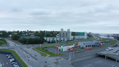 Aufsteigende-Luftaufnahmen-Der-Stadt-Mit-Gebäuden-Und-Verkehrsinfrastruktur.-Küste-Im-Hintergrund.-Reykjavik,-Island
