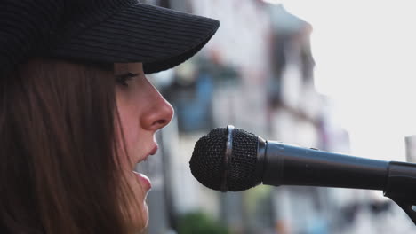 Female-Musician-Busking-Singing-Into-Microphone-Outdoors-In-Street