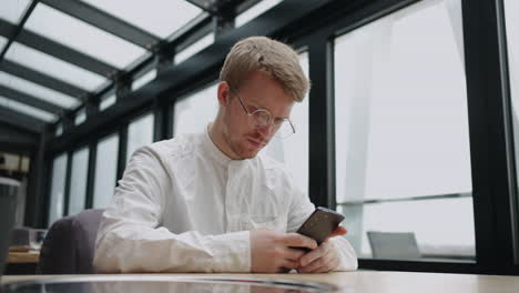 businessman-is-using-smartphone-for-searching-info-in-internet-or-rest-in-social-media-in-cafe-during-lunch-time