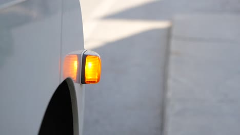 primer plano de una luz de señalización lateral naranja en un vehículo blanco.
