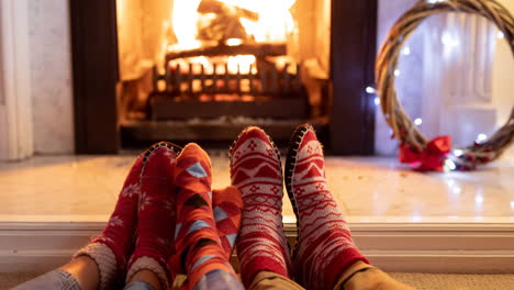 animation of feet of african american family in christmas socks resting in front of fireplace