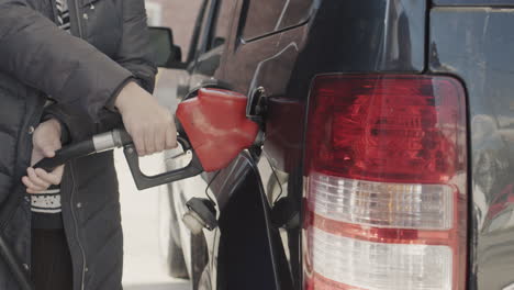 el propietario reabastece de combustible su coche, primer plano de las manos con una pistola de reabastecimiento de combustible