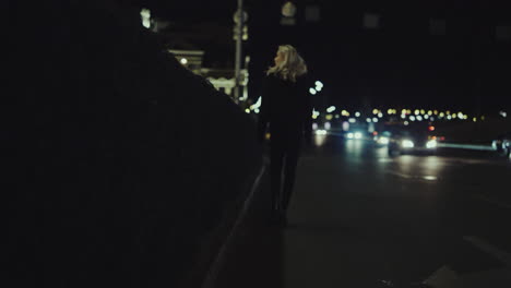 blonde girl going home alone in late night city lights street.