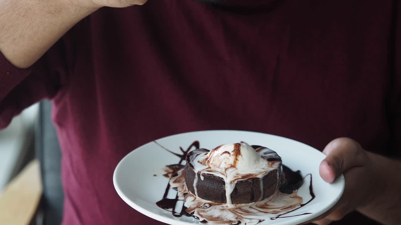 Person eating chocolate lava cake with ice cream