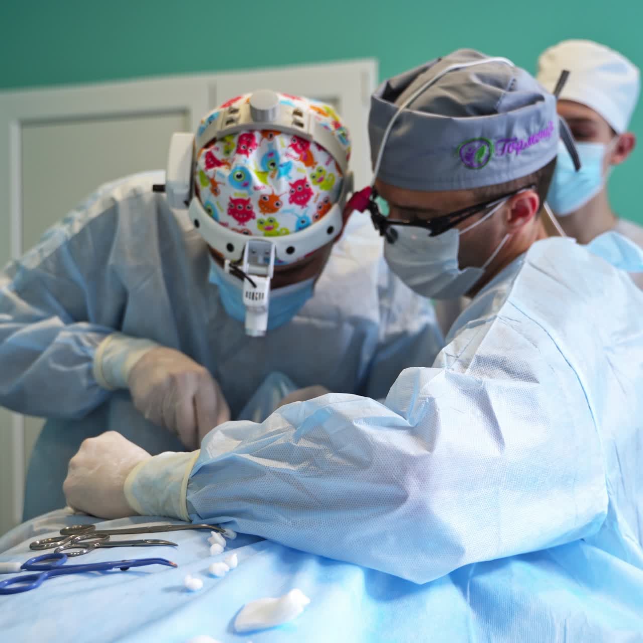 Surgeons working side by side at operation. Female assistant preparing instrument for the doctors. Backdrop in blur