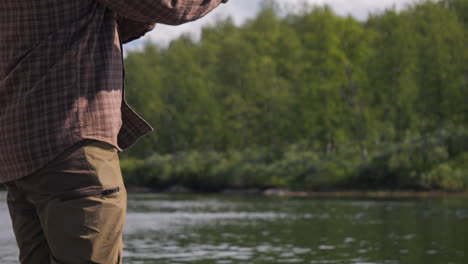 fishing rod spinning reeling in line then throwing, fisherman on river, closeup