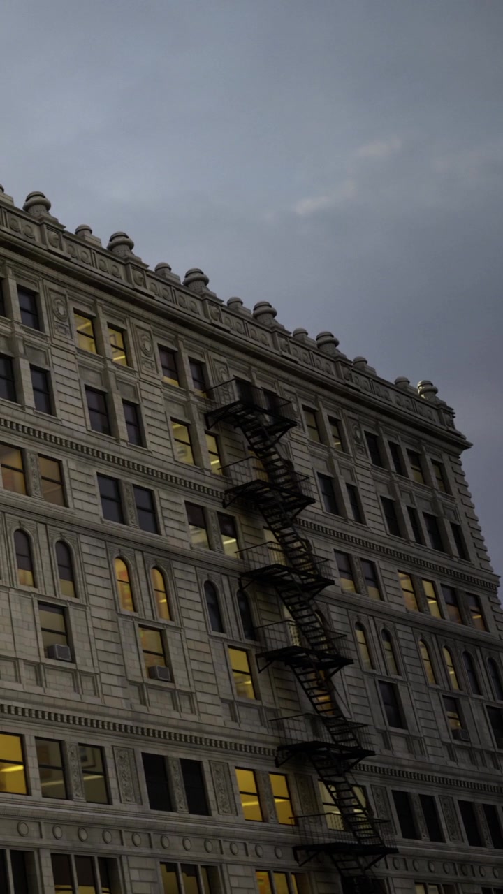 Edificio antiguo con escalera de incendios al anochecer en un entorno urbano.
