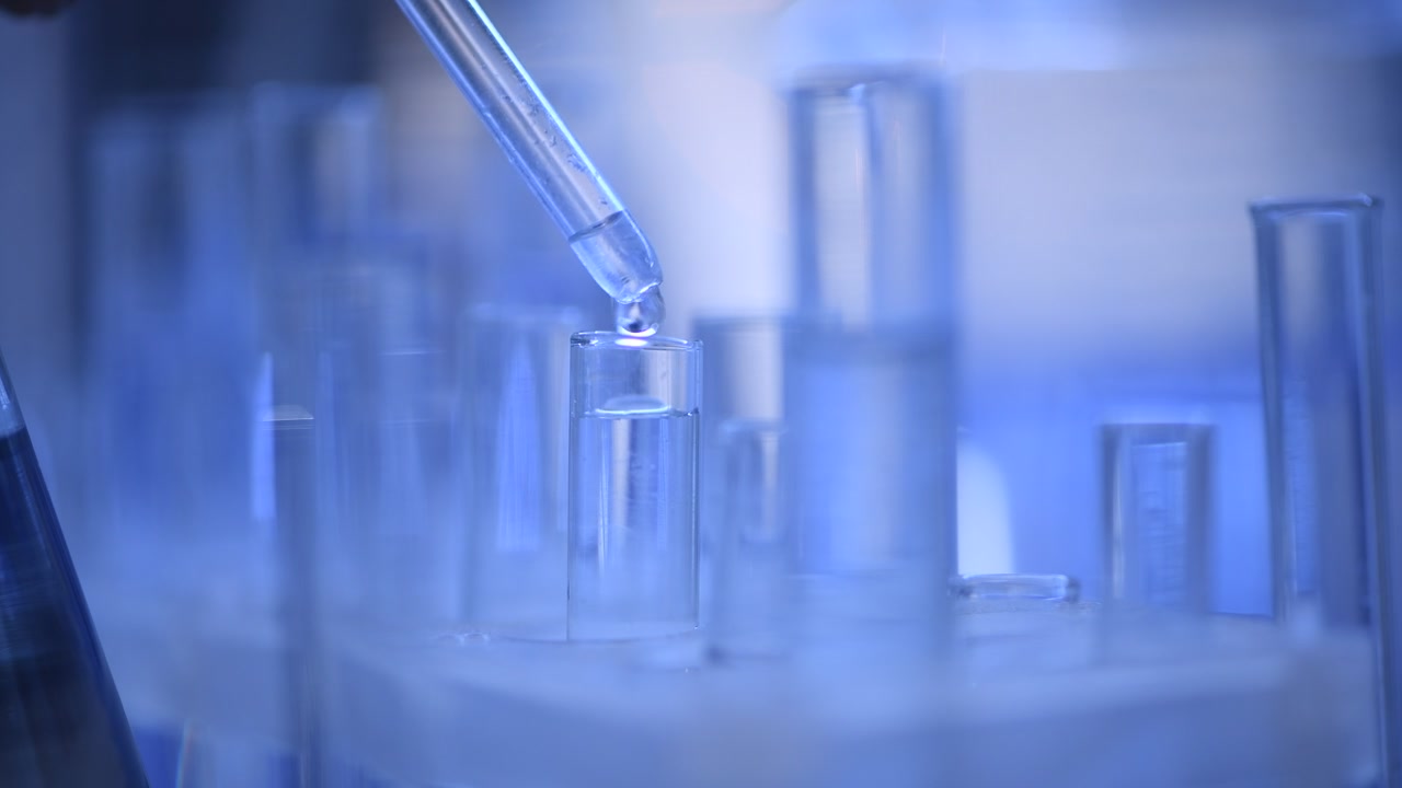 Pipette Dropping Clear Liquid into a Test Tube in a Laboratory