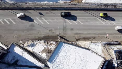 Aerial-view-of-vehicles-circulating-on-the-road-in-a-snowy-town