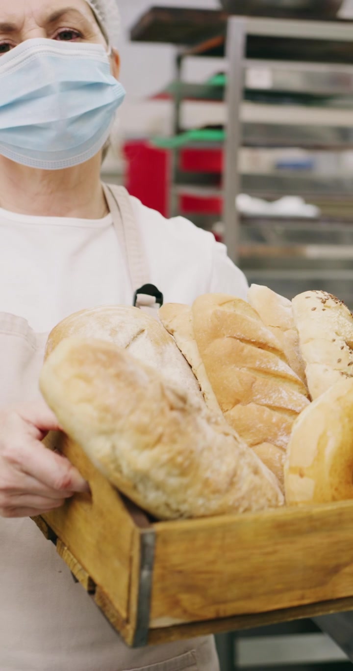 Baker Wearing Face Mask Holding Crate of Fresh Bread