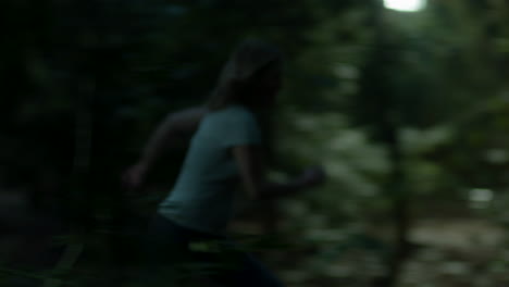 wide shot of scared woman running through a spooky forest at night