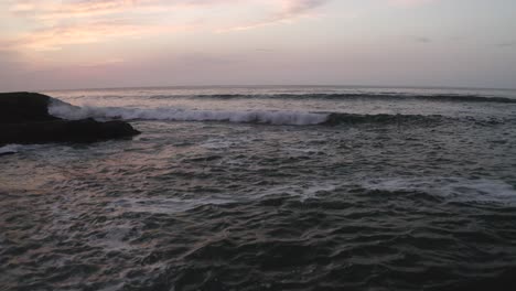 Aerial-flyback-at-low-altitude-over-water-ocean-surface-near-rocky-coast-at-dusk