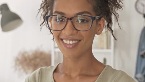 vista de cerca de la feliz mujer bonita en gafas parpadeando con el ojo y mirando a la cámara