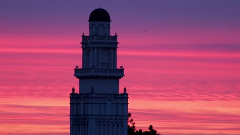 Beautiful,-colorful-twilight-hour-sky-behind-building-with-plane-flying-by