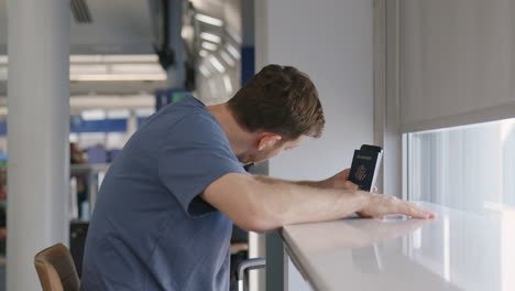 Young-man-holding-passport-waiting-for-his-flight-and-looking-around