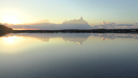 Smooth-Pan-de-las-Salinas-de-Ibiza-with-sunrise-lights-reflected-in-the-water,-Ibiza,-Spain