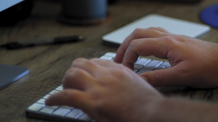 Man works from home at desk with a wireless keyboard