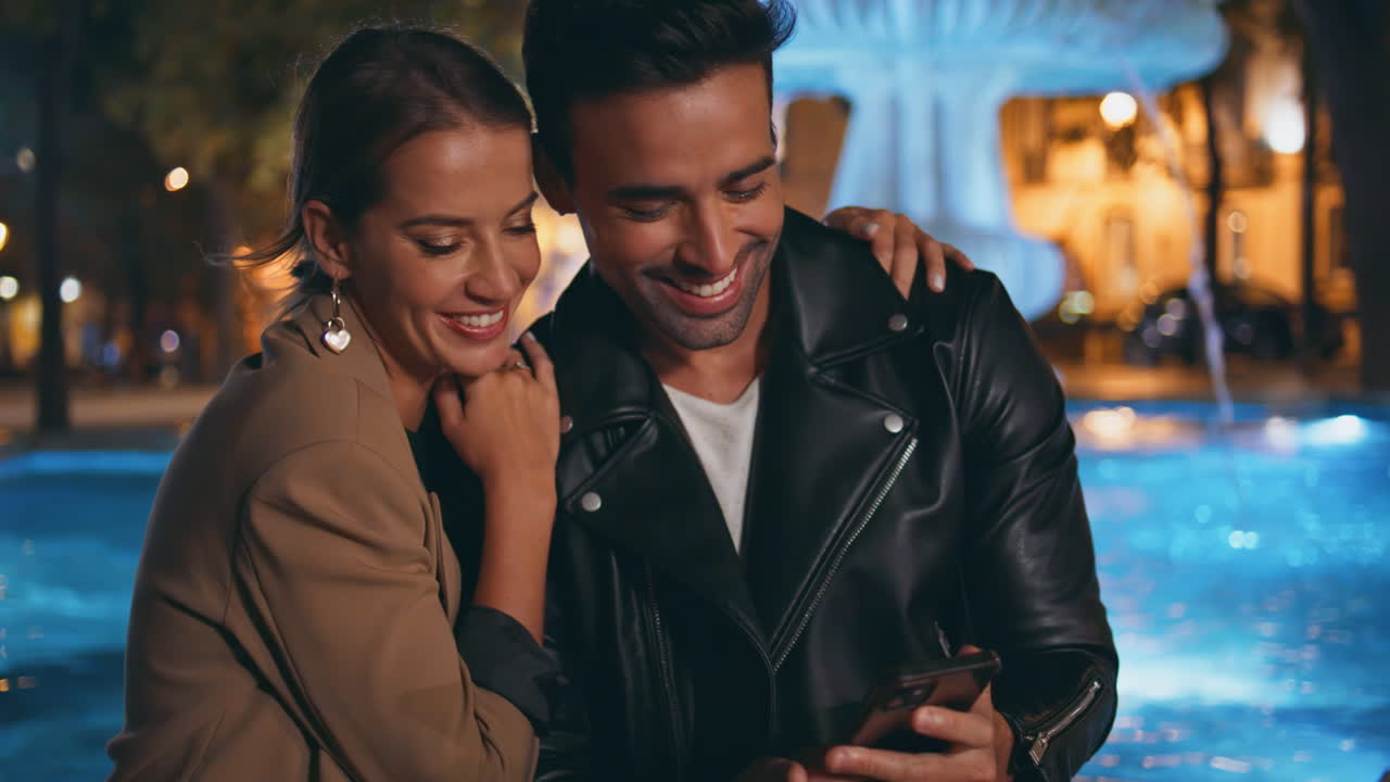 Primo piano di innamorati felici che guardano lo smartphone all'aperto. Coppia innamorata che si diverte.